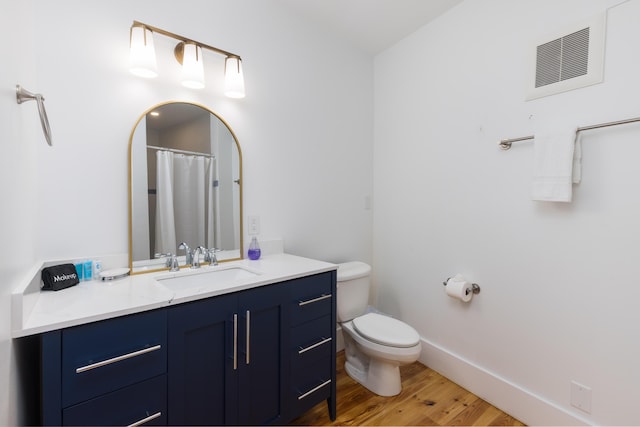 full bathroom featuring toilet, wood finished floors, visible vents, baseboards, and vanity