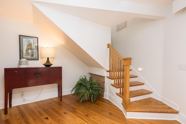staircase with baseboards and wood finished floors