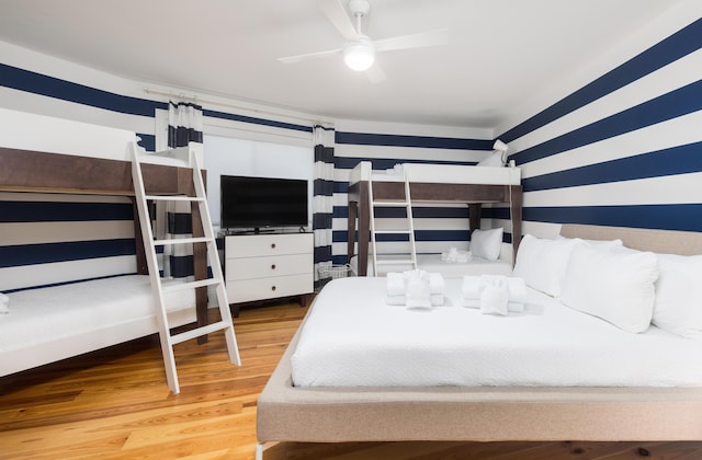 bedroom with wallpapered walls, wood finished floors, and a ceiling fan