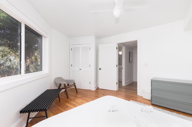bedroom with a closet, wood finished floors, baseboards, and ceiling fan
