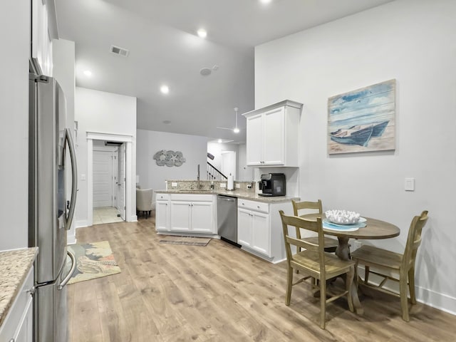 kitchen featuring appliances with stainless steel finishes, sink, white cabinets, kitchen peninsula, and light hardwood / wood-style flooring