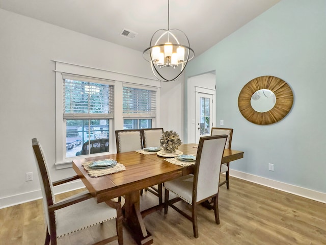 dining space with hardwood / wood-style floors and a chandelier