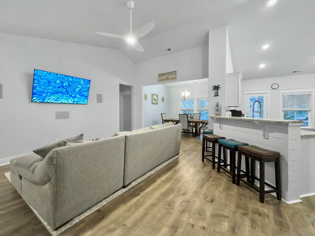 living room featuring vaulted ceiling, hardwood / wood-style flooring, and ceiling fan with notable chandelier