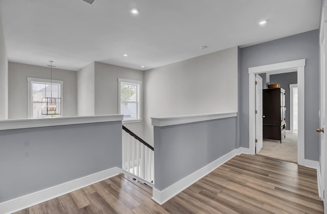 corridor featuring baseboards, plenty of natural light, light wood finished floors, and an upstairs landing