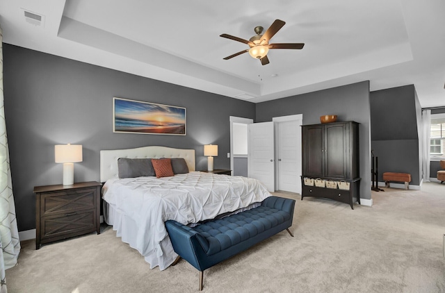 bedroom with baseboards, a tray ceiling, visible vents, and light colored carpet