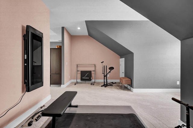 exercise room with lofted ceiling, baseboards, and light colored carpet