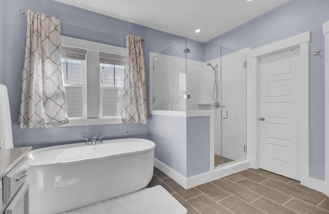 bathroom featuring a stall shower, a soaking tub, and baseboards