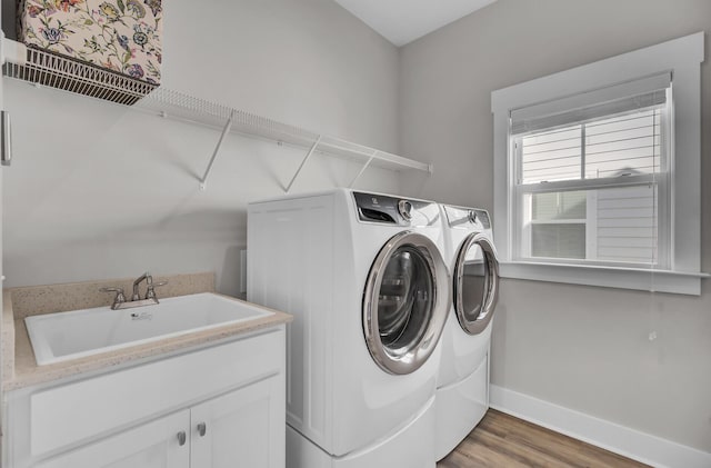 clothes washing area with laundry area, dark wood-type flooring, a sink, baseboards, and washer and dryer