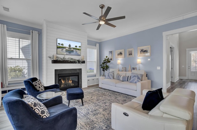 living area featuring a healthy amount of sunlight, visible vents, a fireplace, and wood finished floors