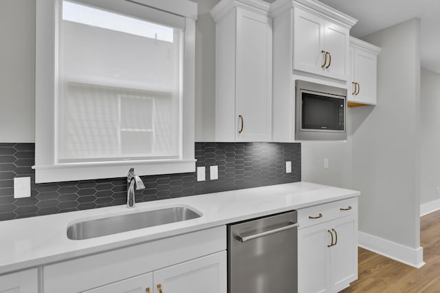 kitchen featuring white cabinetry, sink, backsplash, and stainless steel appliances