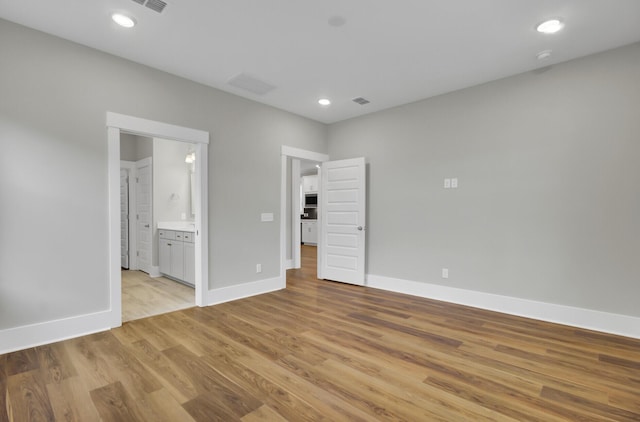 unfurnished bedroom featuring connected bathroom and light wood-type flooring