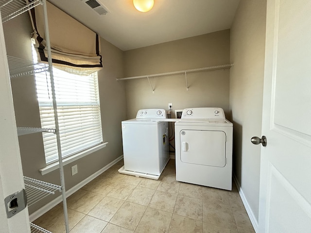 washroom with laundry area, visible vents, baseboards, washing machine and dryer, and light tile patterned flooring