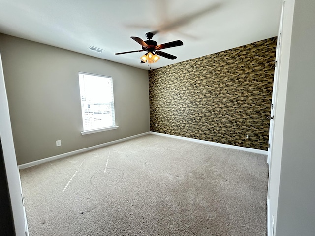 spare room with ceiling fan, baseboards, visible vents, and light colored carpet