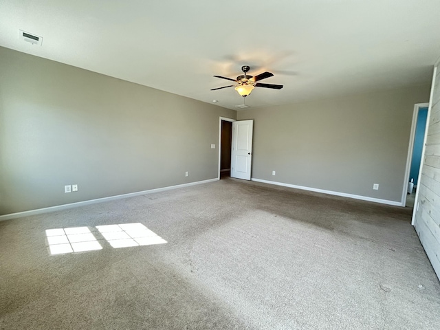 carpeted spare room featuring baseboards, visible vents, and a ceiling fan