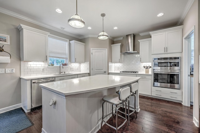 kitchen with a kitchen island, wall chimney range hood, ornamental molding, stainless steel appliances, and a sink