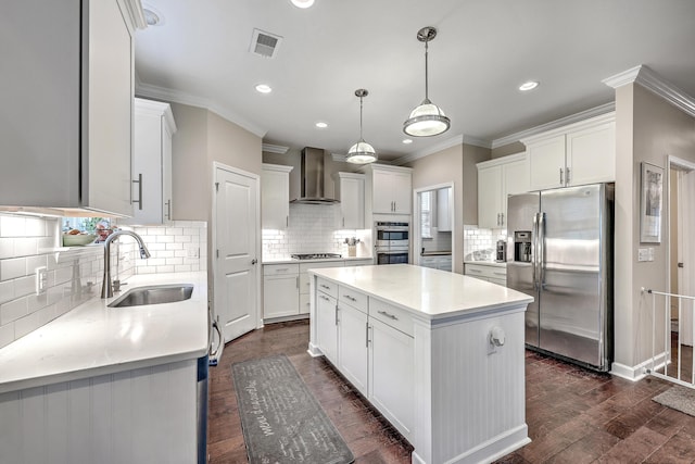 kitchen featuring visible vents, a kitchen island, dark wood-style floors, appliances with stainless steel finishes, and wall chimney exhaust hood