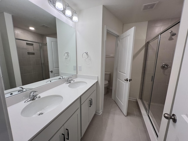 bathroom with a stall shower, visible vents, a sink, and toilet