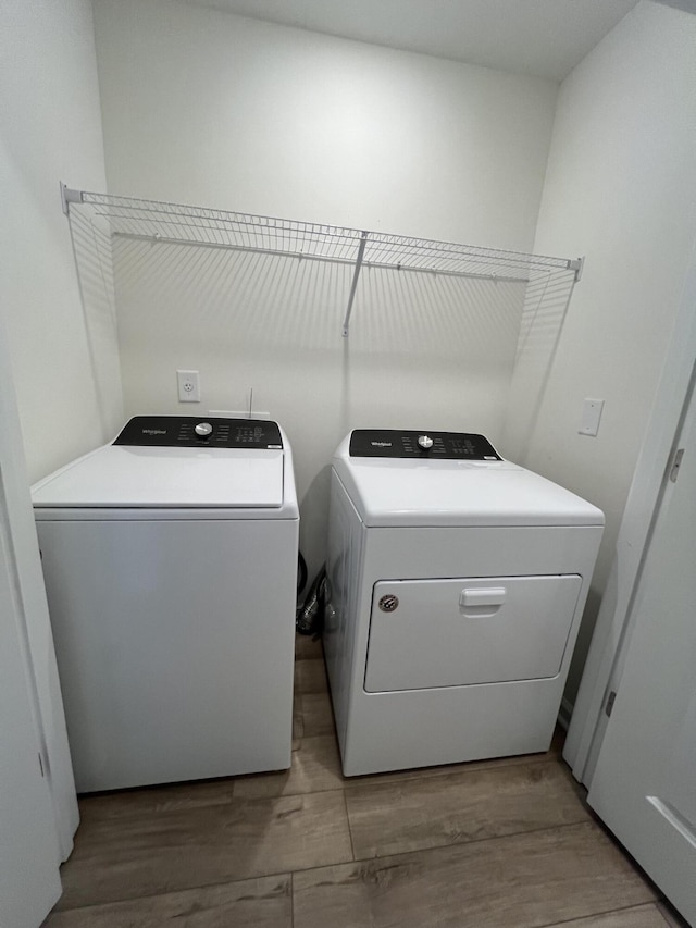 clothes washing area featuring laundry area, wood finished floors, and washing machine and dryer