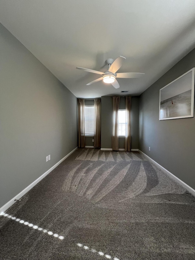 carpeted empty room featuring ceiling fan and baseboards