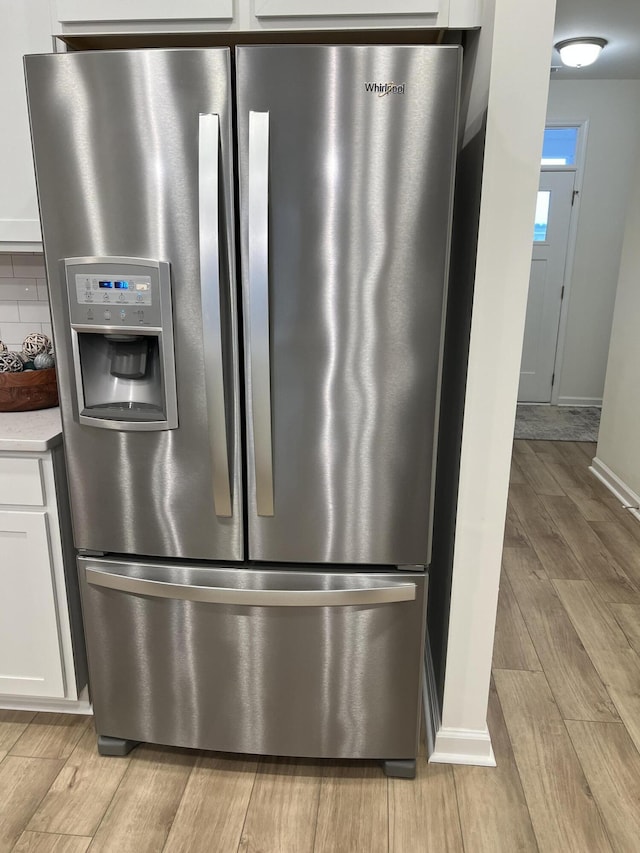 interior details with wood finish floors, white cabinetry, light countertops, stainless steel fridge with ice dispenser, and tasteful backsplash