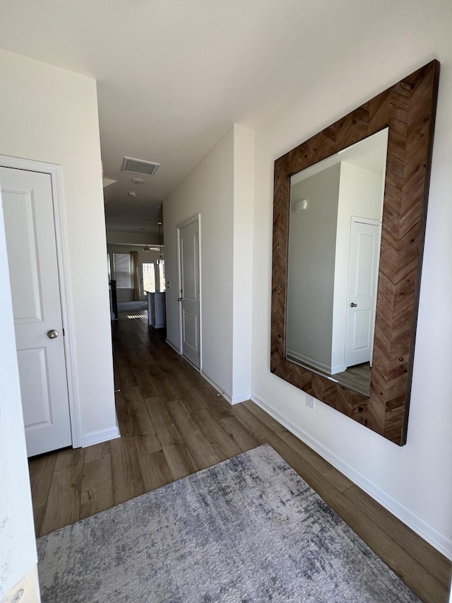 hallway with visible vents, dark wood finished floors, and baseboards