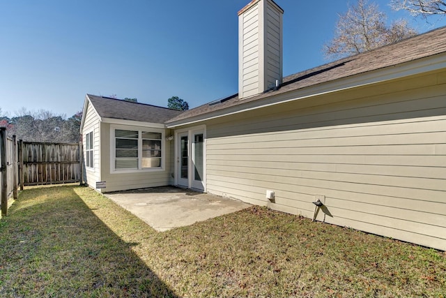 back of house featuring a lawn, a fenced backyard, a chimney, and a patio area