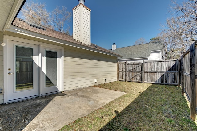 view of yard with a patio, a fenced backyard, and a gate