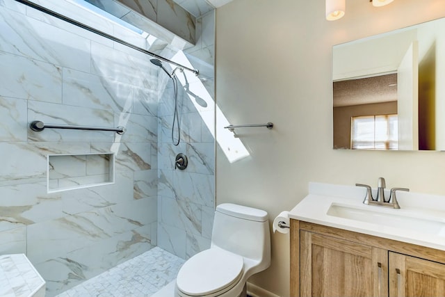 bathroom featuring toilet, vanity, and a tile shower