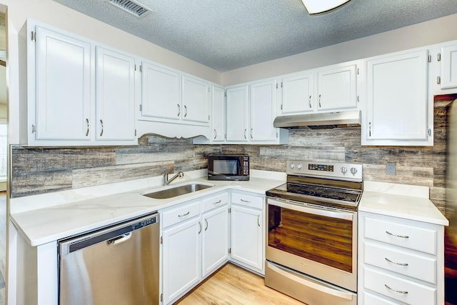 kitchen featuring visible vents, under cabinet range hood, a sink, appliances with stainless steel finishes, and light countertops