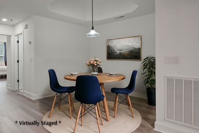 dining room featuring wood-type flooring and a tray ceiling