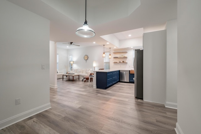 kitchen featuring decorative light fixtures, blue cabinets, a kitchen bar, light hardwood / wood-style floors, and stainless steel appliances