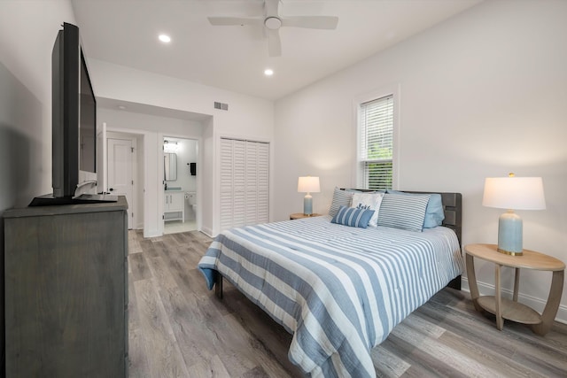 bedroom with ensuite bathroom, ceiling fan, light wood-type flooring, and a closet