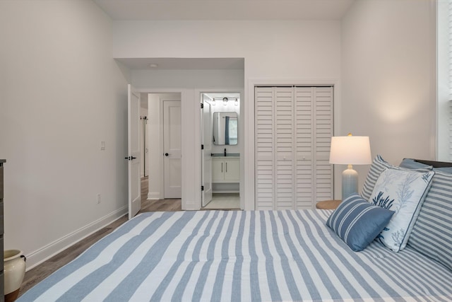 bedroom featuring hardwood / wood-style floors, ensuite bath, and a closet