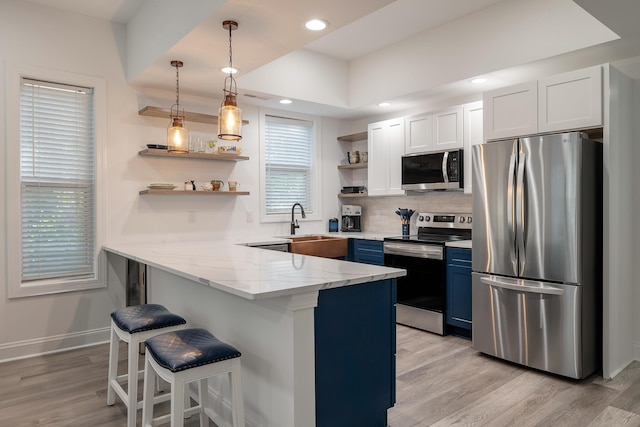 kitchen with blue cabinetry, a kitchen bar, white cabinetry, kitchen peninsula, and stainless steel appliances