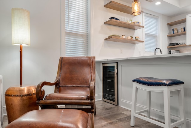 living area featuring bar, beverage cooler, and light hardwood / wood-style flooring