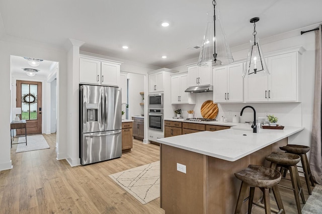 kitchen with a breakfast bar, a peninsula, a sink, stainless steel appliances, and under cabinet range hood