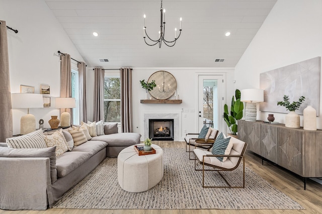 living room with light hardwood / wood-style flooring, a notable chandelier, high vaulted ceiling, and a fireplace