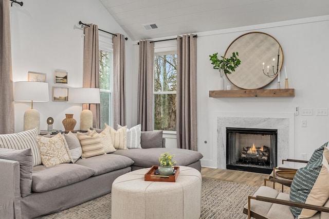 living area featuring visible vents, lofted ceiling, wood finished floors, and a fireplace