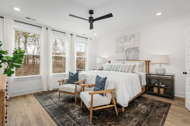 bedroom with dark wood-type flooring, multiple windows, ceiling fan, and crown molding