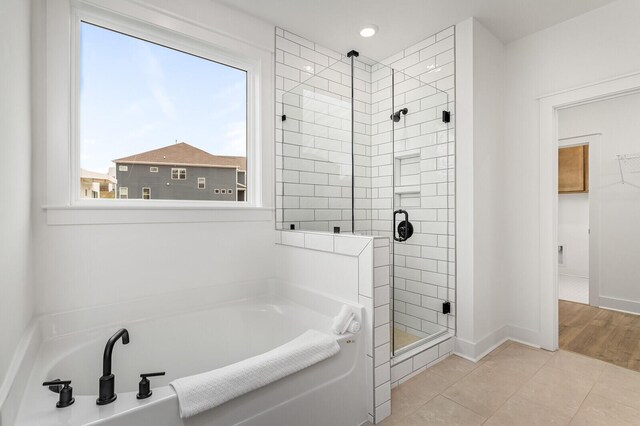 full bathroom featuring baseboards, a stall shower, a walk in closet, a garden tub, and tile patterned floors