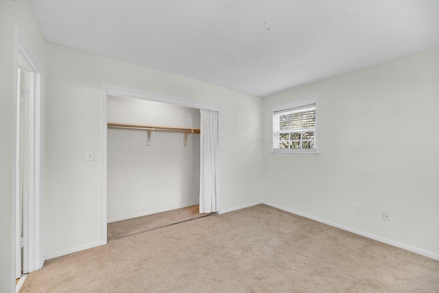 unfurnished bedroom with a closet, a textured ceiling, baseboards, and carpet