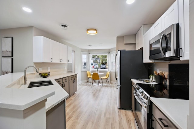 1161 Monaco Dr, Mount Pleasant, SC 29464 - kitchen with stainless steel appliances, a peninsula, light countertops, white cabinetry, and light wood-style floors