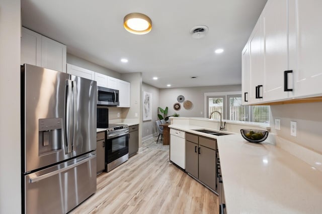 1161 Monaco Dr, Mount Pleasant, SC 29464 - kitchen featuring appliances with stainless steel finishes, white cabinets, light countertops, light wood-style floors, and a peninsula