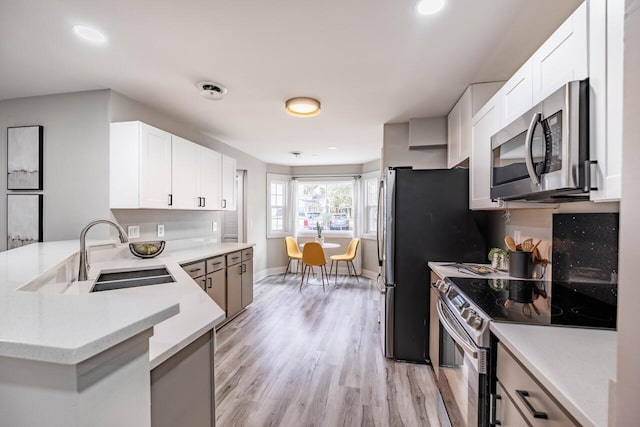 1161 Monaco Dr, Mount Pleasant, SC 29464 - kitchen with stainless steel appliances, a peninsula, light countertops, light wood-type flooring, and white cabinets