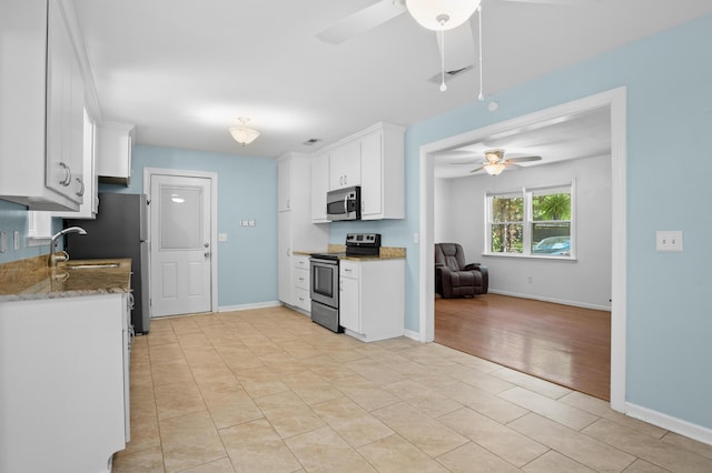 kitchen with ceiling fan, appliances with stainless steel finishes, light stone countertops, baseboards, and white cabinetry