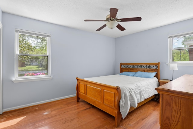 bedroom with light wood-style floors, baseboards, and multiple windows