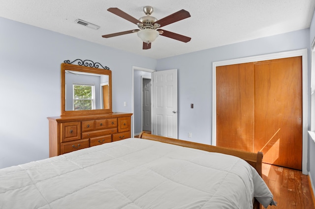 bedroom with a ceiling fan, wood finished floors, and visible vents
