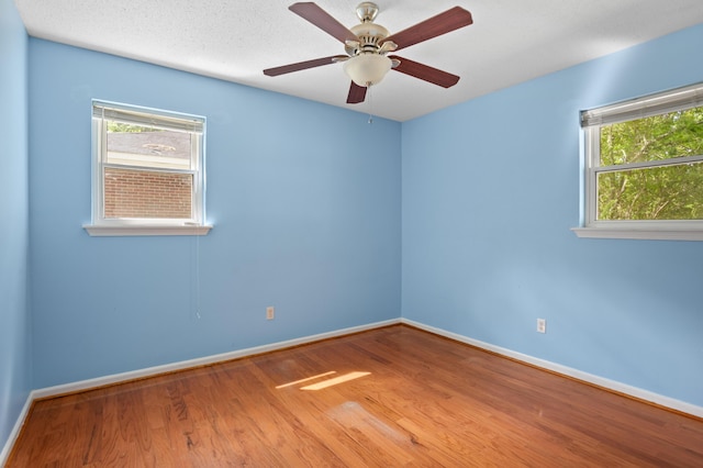 empty room with baseboards, ceiling fan, plenty of natural light, and wood finished floors