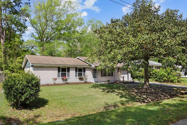 view of front of home featuring brick siding, a shingled roof, a front lawn, and a garage