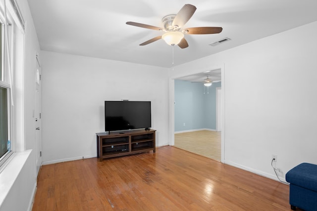 unfurnished living room with baseboards, ceiling fan, wood finished floors, and visible vents